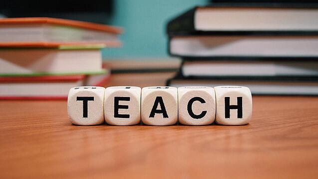Buchstabenbauklötze bilden das Wort "Teach".