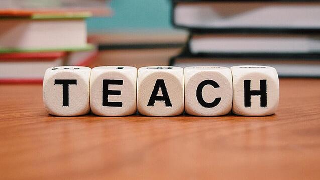 Buchstabenbauklötze bilden das Wort "Teach".