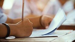 Hände schreiben etwas auf ein Blatt Papier.