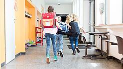 Kinder rennen auf dem Flur einer Schule.