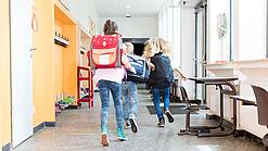 Kinder rennen auf dem Flur einer Schule.