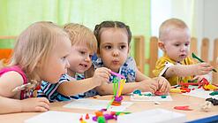 Kleinkinder sitzen an einem Tisch und spielen.