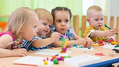 Kleinkinder sitzen an einem Tisch und spielen.