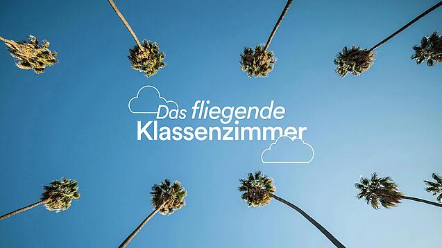 "Das fliegende Klassenzimmer" steht in weißer Schrift auf dem blauen Himmel, umrandet von Palmen.