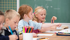 Kinder sitzen in der Grundschule an einem Tisch und lernen Mathematik.