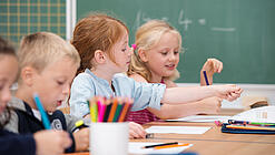 Kinder sitzen in der Grundschule an einem Tisch und lernen Mathematik.