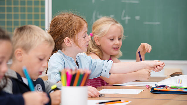 Kinder sitzen in der Grundschule an einem Tisch und lernen Mathematik.