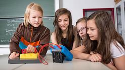 Vier Schüler:innen schauen auf ein Experiment.