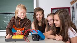 Vier Schüler:innen schauen auf ein Experiment.