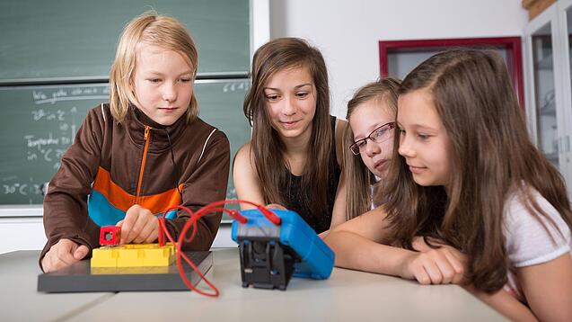 Vier Schüler:innen schauen auf ein Experiment.