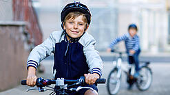 Ein Kind fährt mit Fahrradhelm auf einem Fahrrad.