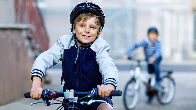 Ein Kind fährt mit Fahrradhelm auf einem Fahrrad.