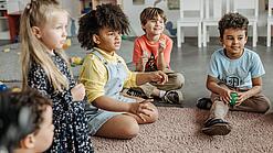 Kindergartenkinder sitzen in einem Kreis.