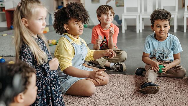 Kindergartenkinder sitzen in einem Kreis.