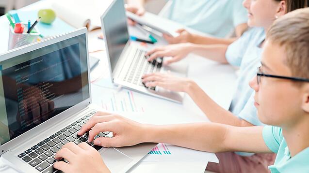 Schüler sitzt an einem Laptop und schreibt.