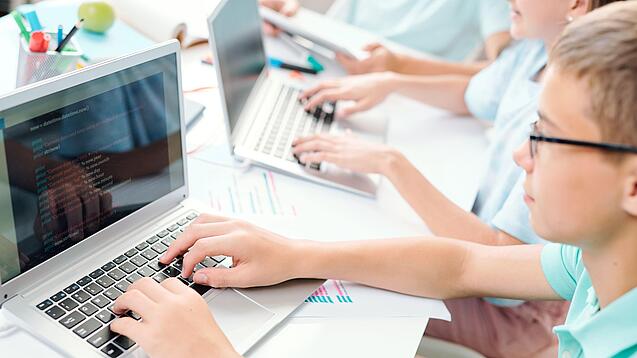 Schüler sitzt an einem Laptop und schreibt.