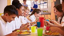 Schulkinder sitzen an einem Tisch und essen.