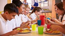 Schulkinder sitzen an einem Tisch und essen.