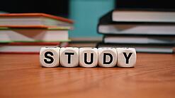 Buchstabenwürfel bilden das Wort "Study" auf einem Tisch.