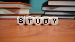 Buchstabenwürfel bilden das Wort "Study" auf einem Tisch.