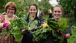 Mehrere Frauen halten Gemüse in den Händen und lächeln in die Kamera.