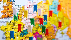 In einen Ausschnitt einer Karte von Europa sind mehrere verschiedenfarbene Fähnchen gepinnt, die verschiedene Orte symbolisieren.