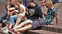 Jugendliche schauen auf dem Schulhof auf ihr Smartphone.