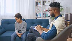 Mann mit Klemmbrett und Junge sitzen sich gegenüber