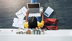 Junge Frau am Laptop vor einem Bücherregal.