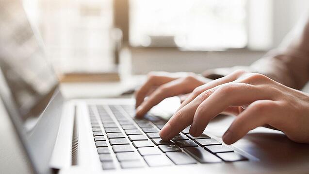 Eine Person tippt auf einer Laptop-Tastatur.