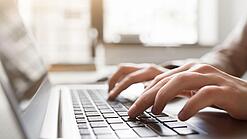 Eine Person tippt auf einer Laptop-Tastatur.