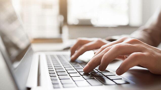 Eine Person tippt auf einer Laptop-Tastatur.
