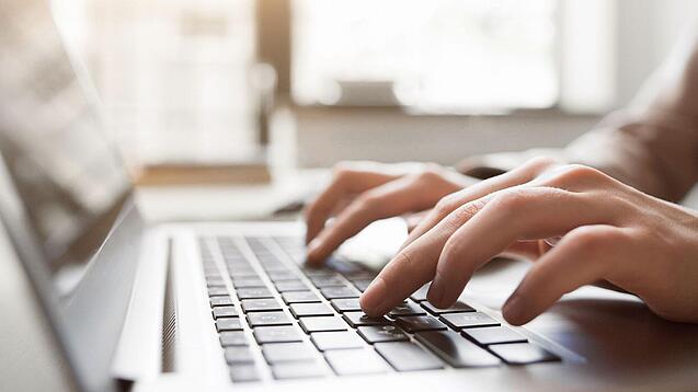 Eine Person tippt auf einer Laptop-Tastatur.