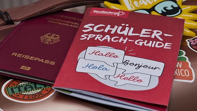 Eine Buchausgabe des Sprachguides liegt auf einem deutschen Reisepass. Beides liegt auf einem Tisch.