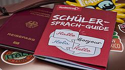 Eine Buchausgabe des Sprachguides liegt auf einem deutschen Reisepass. Beides liegt auf einem Tisch.