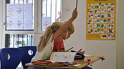 Eine Grundschülerin und ein Grundschüler sitzen im Unterricht.