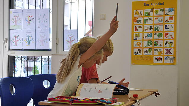 Eine Grundschülerin und ein Grundschüler sitzen im Unterricht.