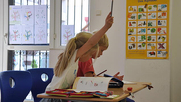 Eine Grundschülerin und ein Grundschüler sitzen im Unterricht.