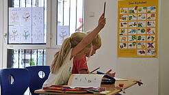 Eine Grundschülerin und ein Grundschüler sitzen im Unterricht.