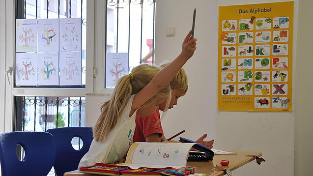 Eine Grundschülerin und ein Grundschüler sitzen im Unterricht.