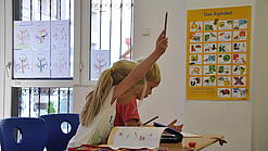 Eine Grundschülerin und ein Grundschüler sitzen im Unterricht.