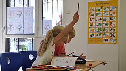 Eine Grundschülerin und ein Grundschüler sitzen im Unterricht.