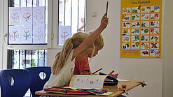 Eine Grundschülerin und ein Grundschüler sitzen im Unterricht.