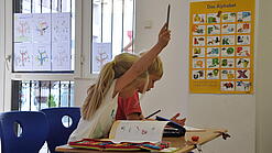 Eine Grundschülerin und ein Grundschüler sitzen im Unterricht.