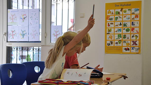 Eine Grundschülerin und ein Grundschüler sitzen im Unterricht.