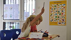 Eine Grundschülerin und ein Grundschüler sitzen im Unterricht.