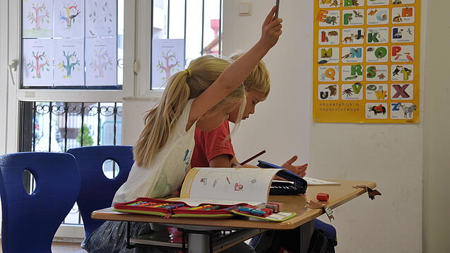 Eine Grundschülerin und ein Grundschüler sitzen im Unterricht.