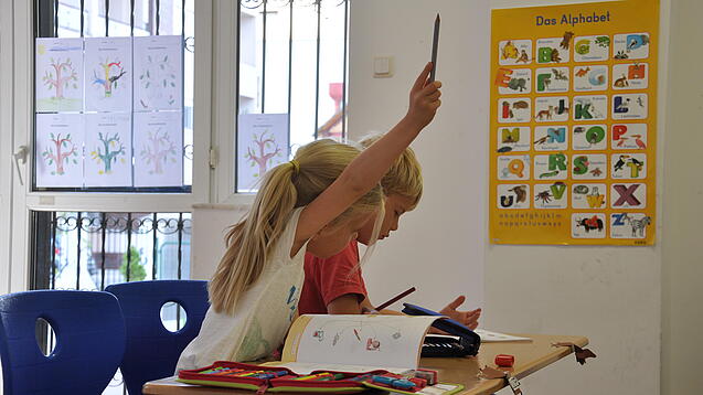 Eine Grundschülerin und ein Grundschüler sitzen im Unterricht.