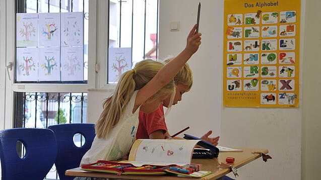 Eine Grundschülerin und ein Grundschüler sitzen im Unterricht.