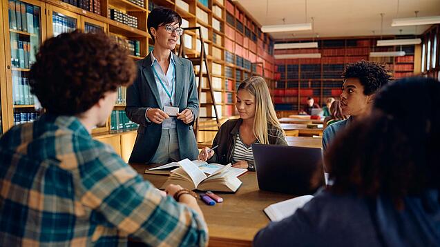 Gruppe Schüler und eine Lehrerin in einer Bibliothek